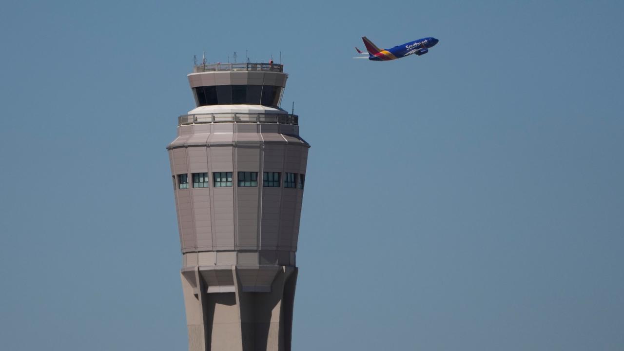 A plane takes off near an air traffic control tower