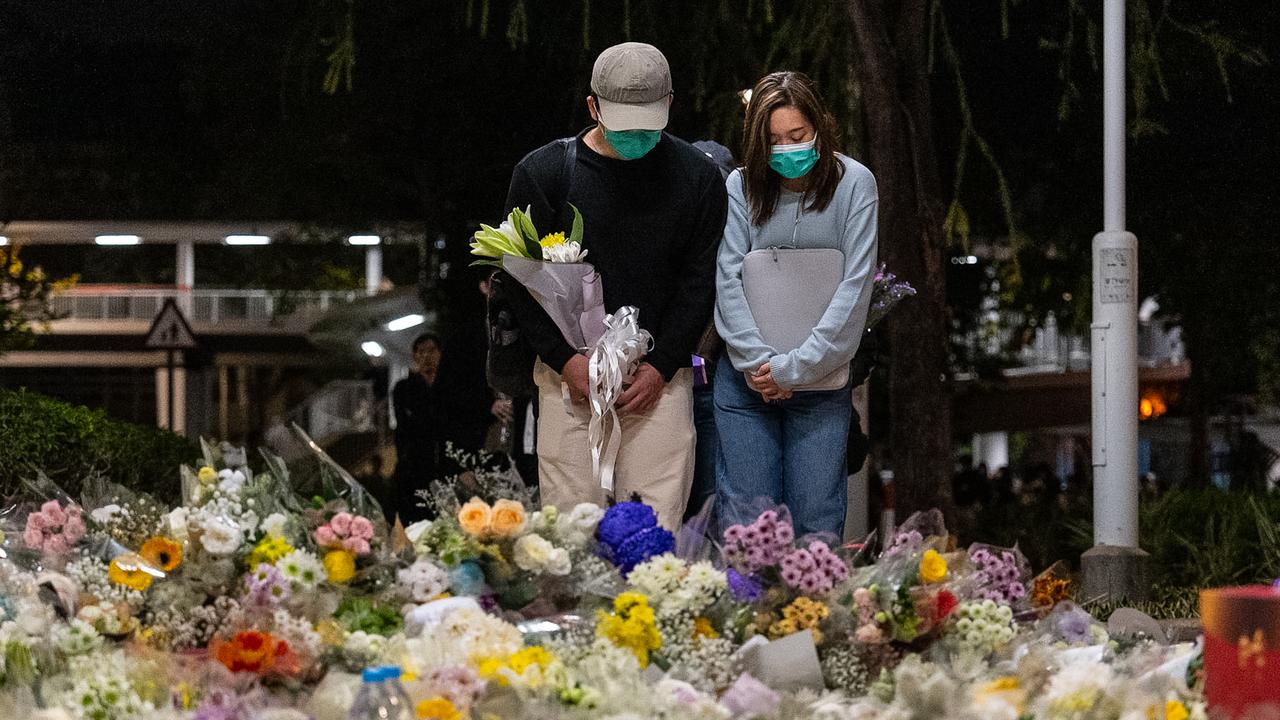People lay flowers near the site to mourn the victims of the fire