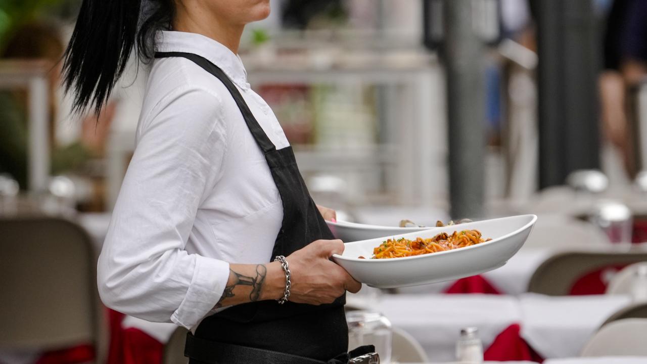 A waitress serves pasta in a restaurant