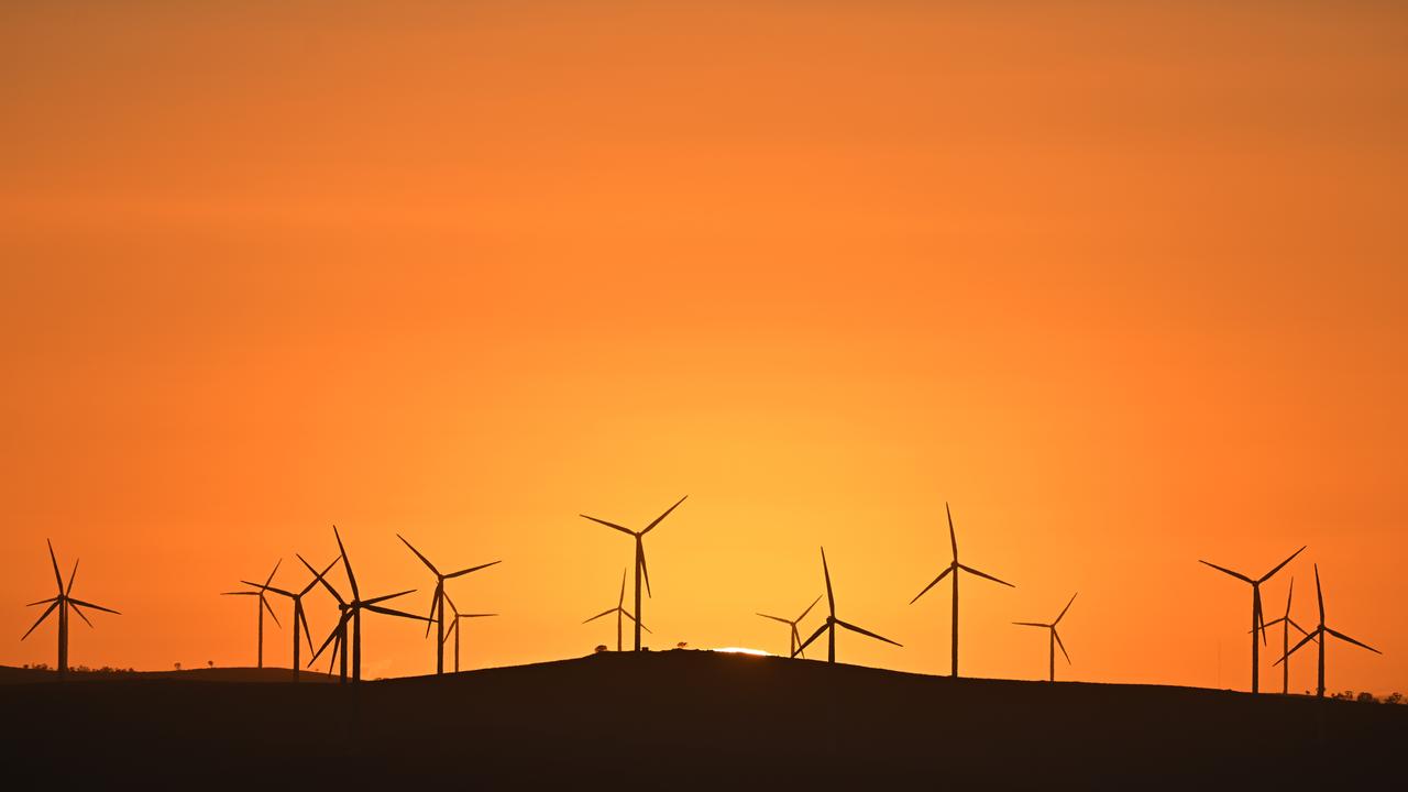 The sun rises over power-generating wind turbines