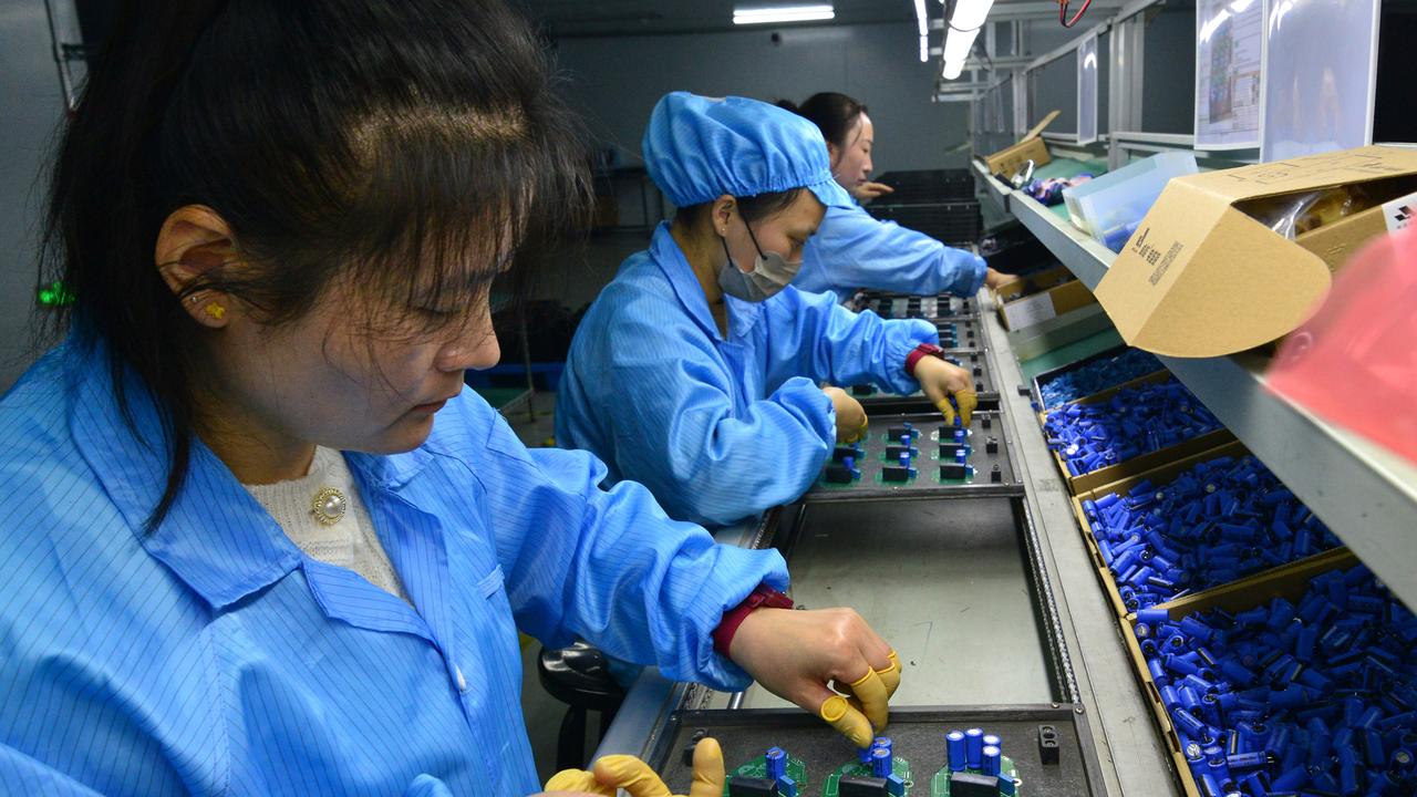 Workers install printed circuit board at an electronics factory