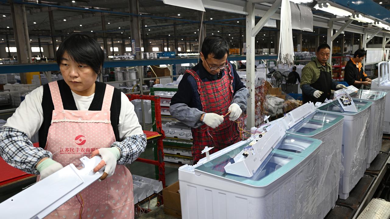 Workers install washing machines at a factory
