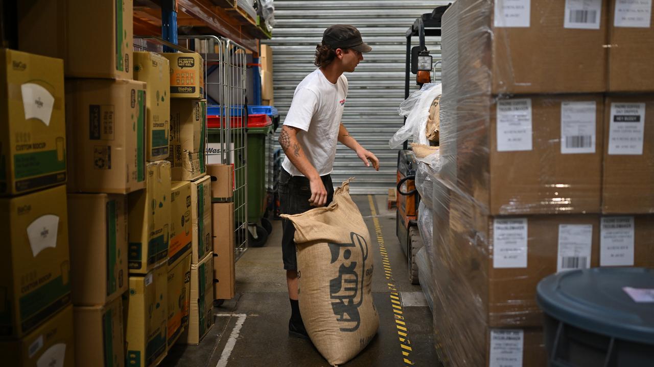 Ethan Slater handing a bag of green coffee beans