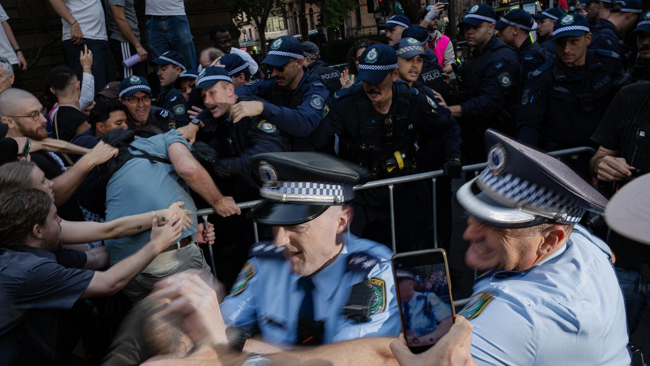 Police officers detain demonstrators during a protest