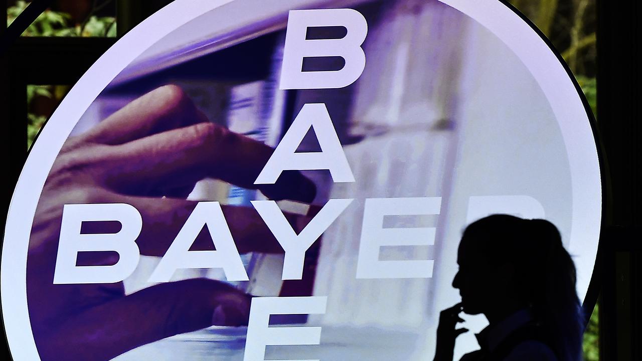 A woman walks in front of a logo of Bayer