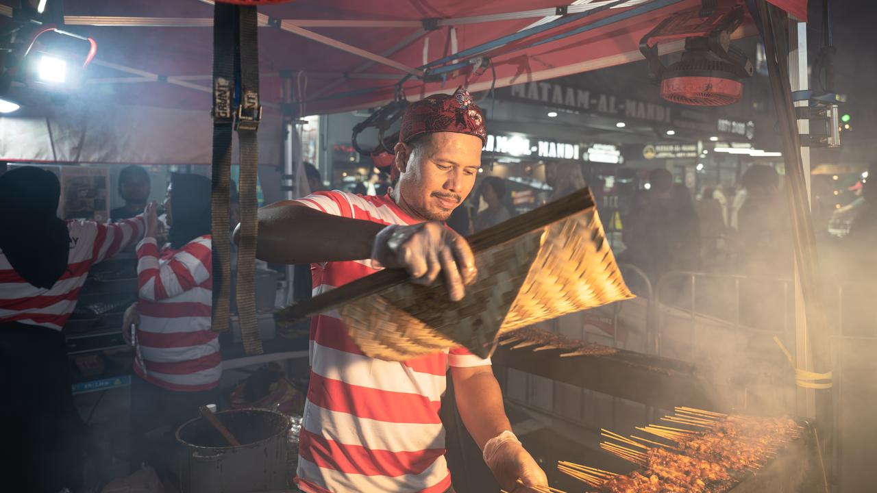 A vendor prepares grilled meat skewers in Sydney
