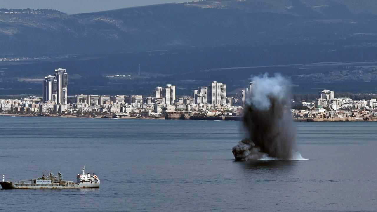 A smoke plume rises as an Iranian missile hits waters off Israel