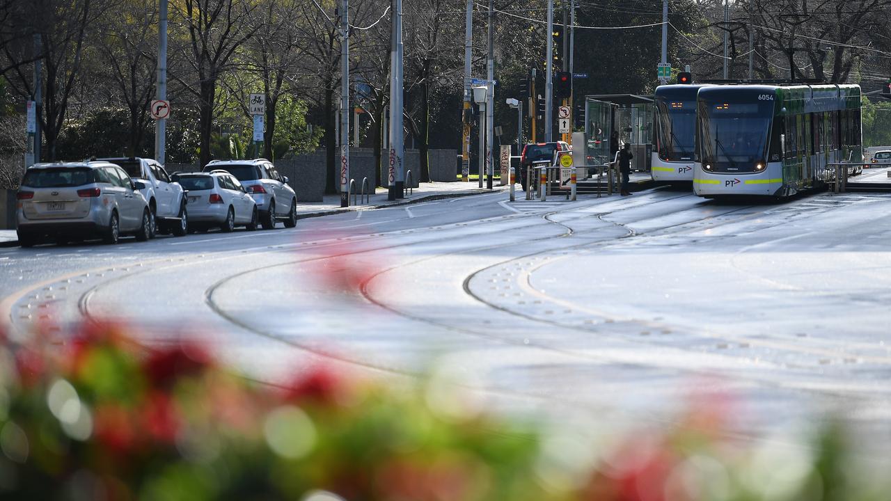 Trams are seen along a near empty road in Melbourne