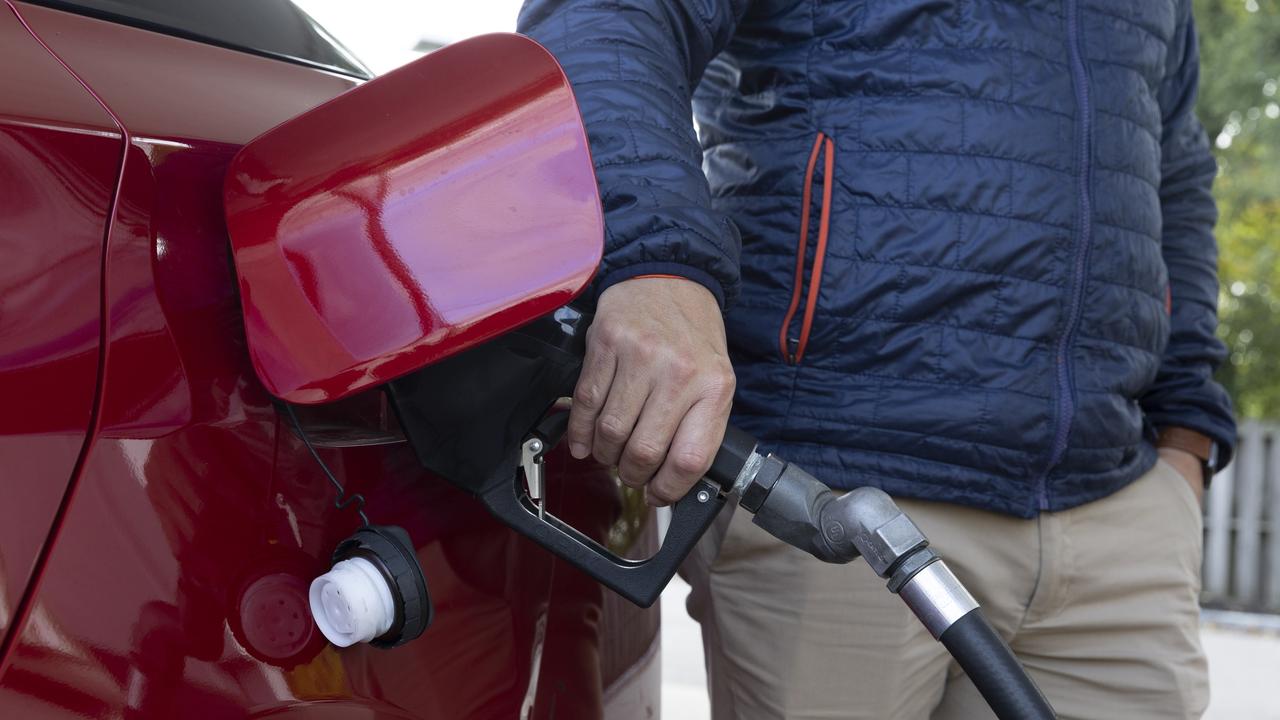 A man pumps petrol into his red car