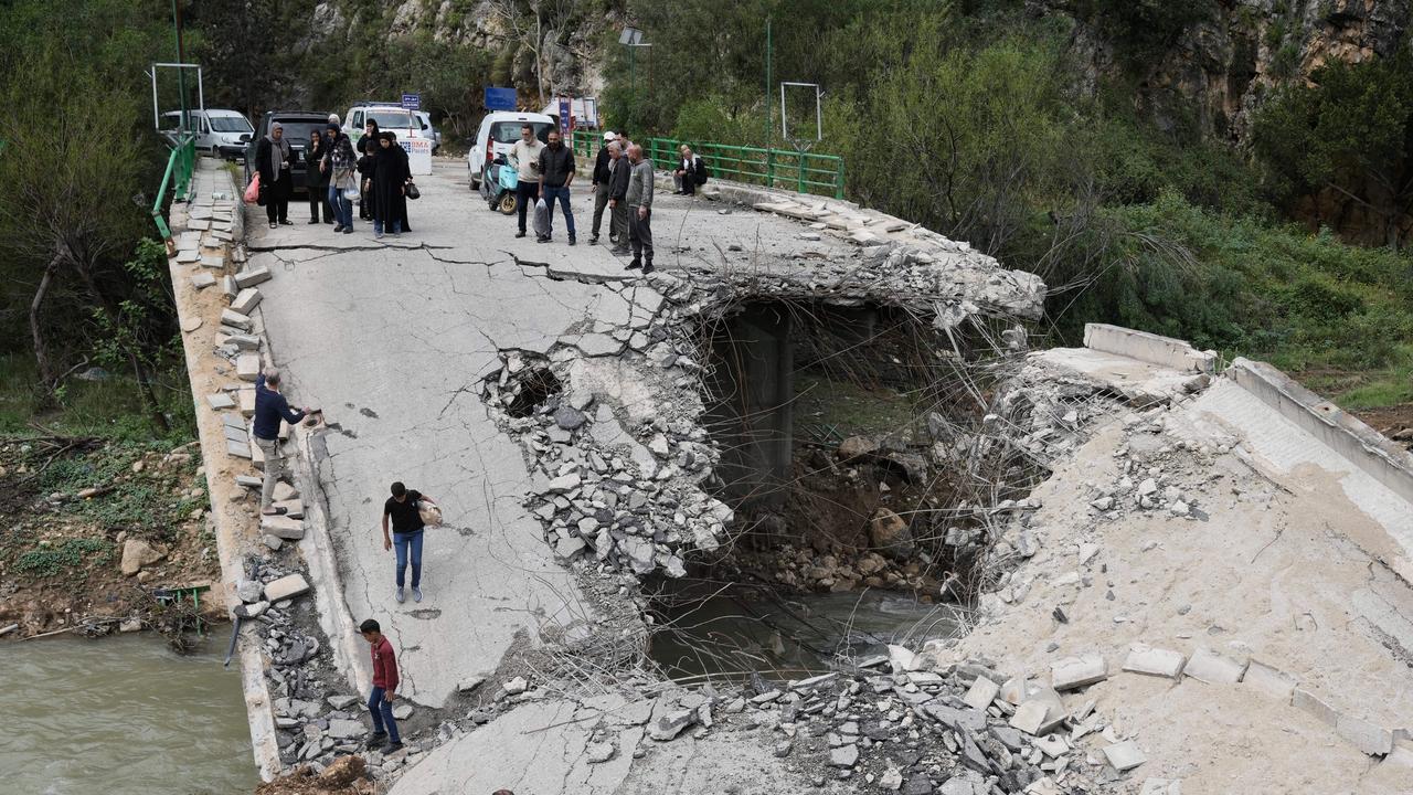 Displaced people cross a destroyed bridge in Lebanon