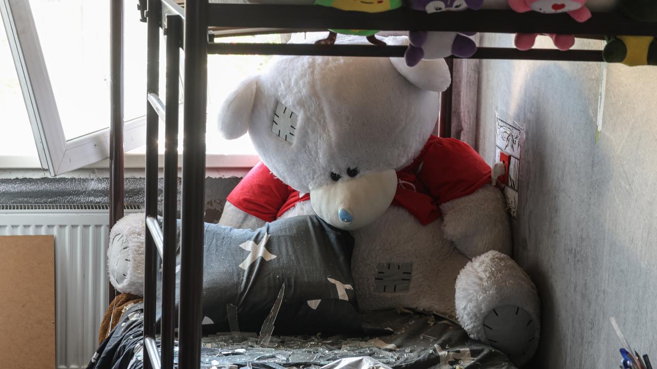 A teddy bear on a bunk bed in a dorm room