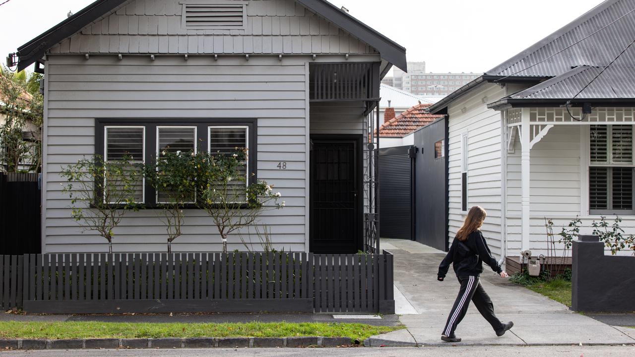 A woman walks past a house in Melbourne