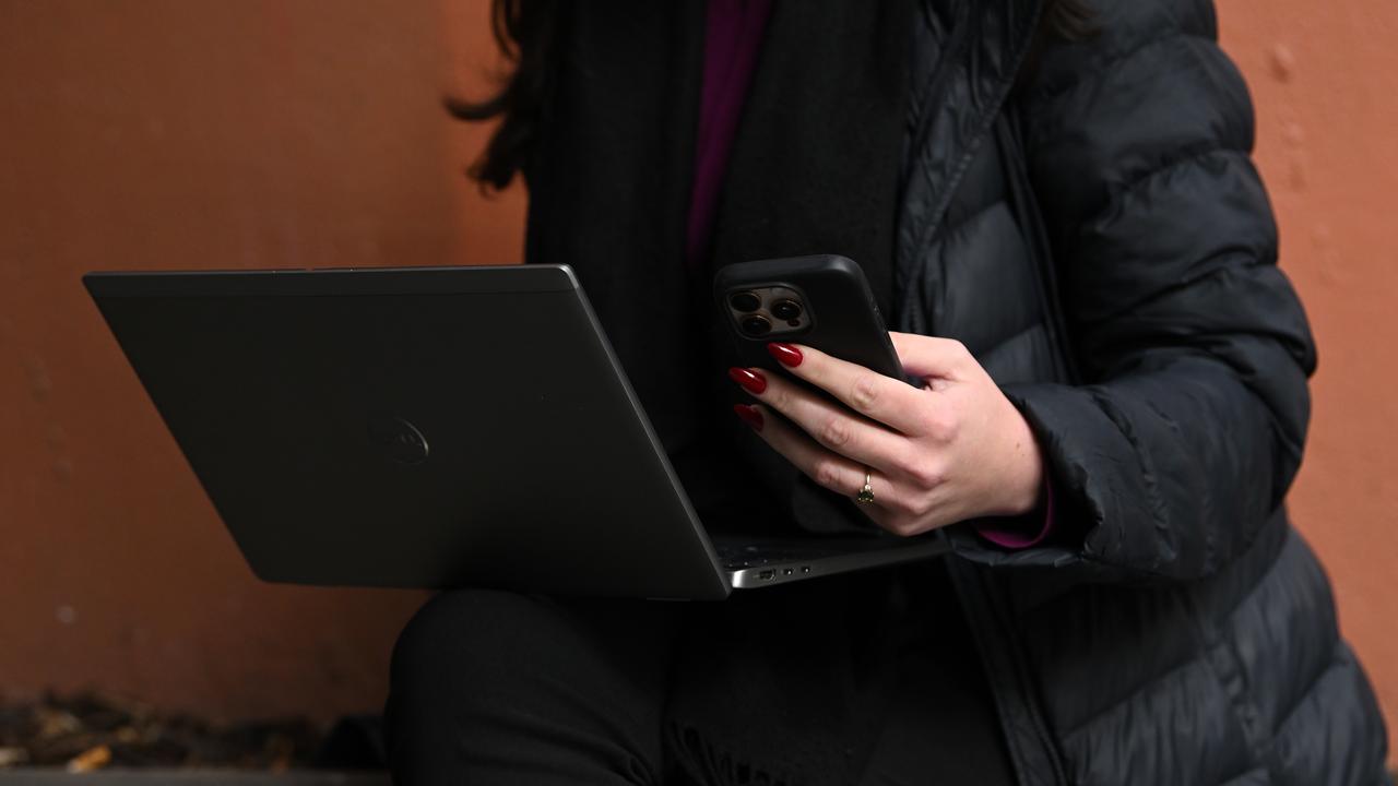 A person holds a mobile phone and laptop (file image)