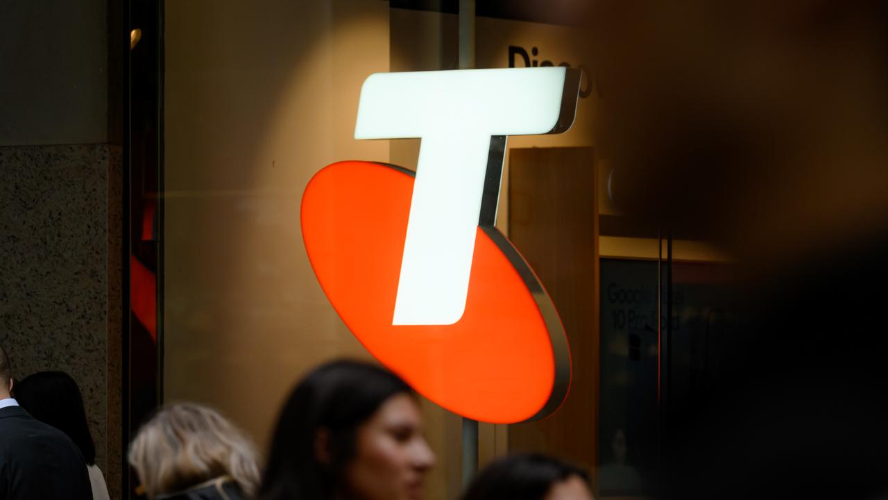 People walking past Telstra signage
