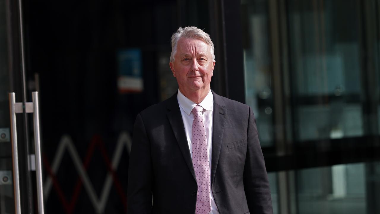 Martin Foley in a suit walks out of court