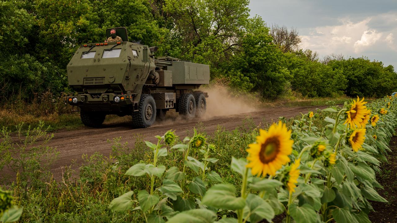 A Ukrainian vehicle passes sunflowers on the way to the frontline